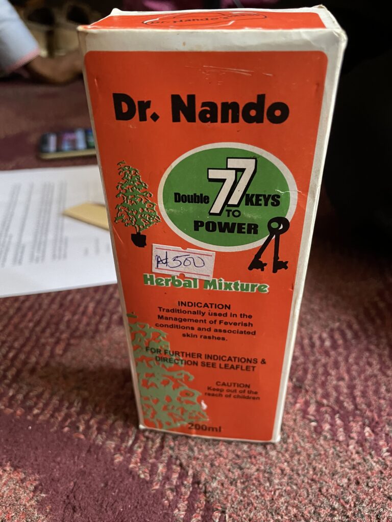 Red medicine packaging - labelled "Dr Nando Double 77 KEYS TO POWER, Herbal Mixture. INDICATION: Traditionally used in the Management of Feverish conditions and associated diseases. For further indications & direction see leaflet." The box includes a picture of a green plant.